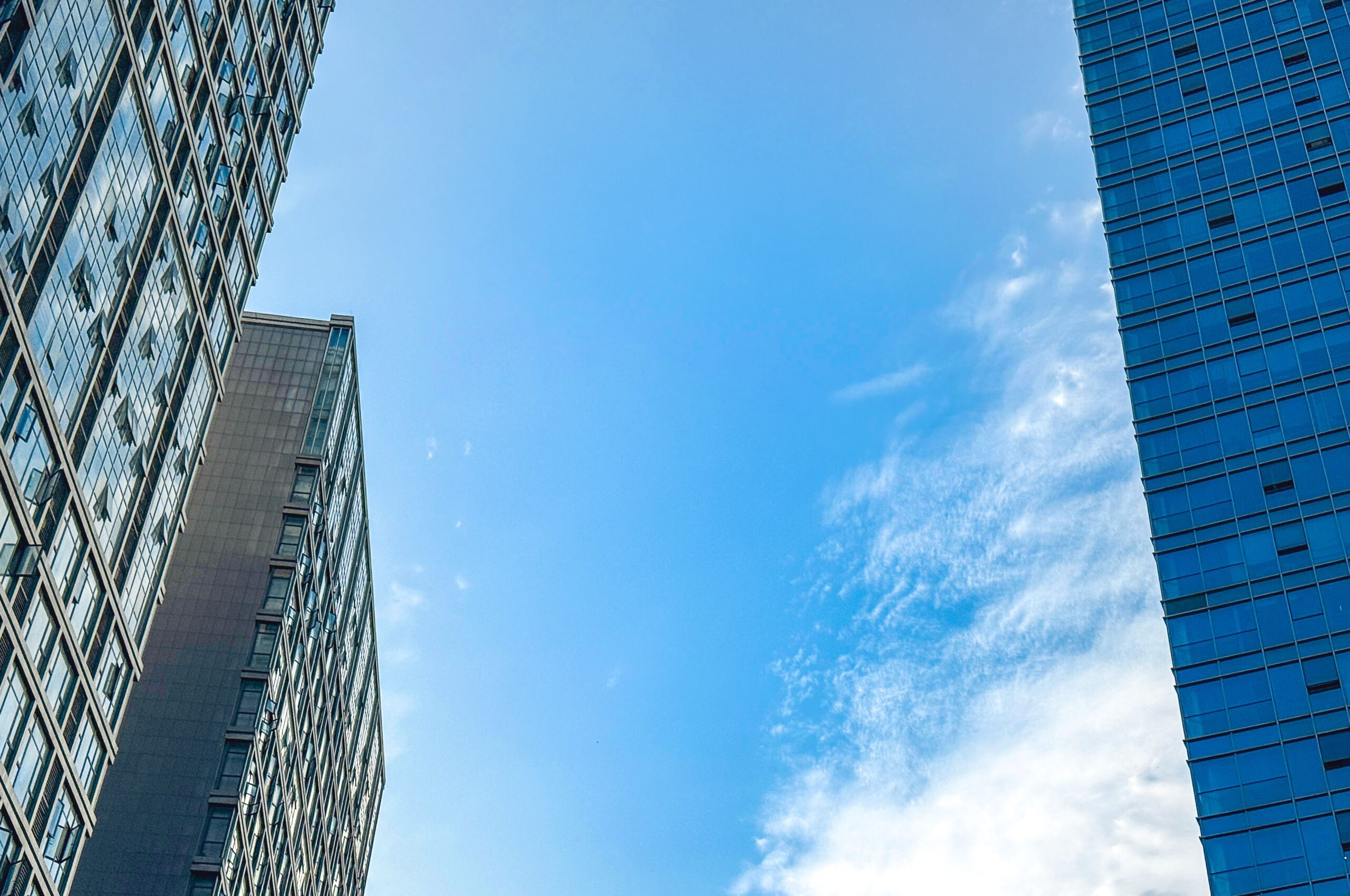 Modern skyscrapers reaching into a clear blue sky with wispy clouds.